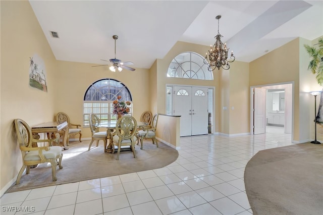 foyer entrance featuring a towering ceiling, light tile patterned flooring, and ceiling fan with notable chandelier