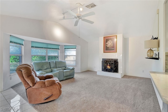 carpeted living room with ceiling fan, lofted ceiling, and a tiled fireplace