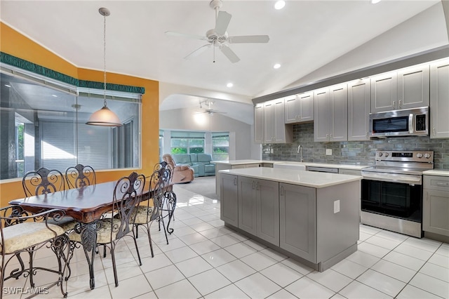 kitchen with appliances with stainless steel finishes, backsplash, gray cabinets, hanging light fixtures, and lofted ceiling