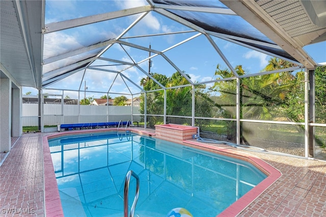 view of swimming pool featuring glass enclosure and a patio