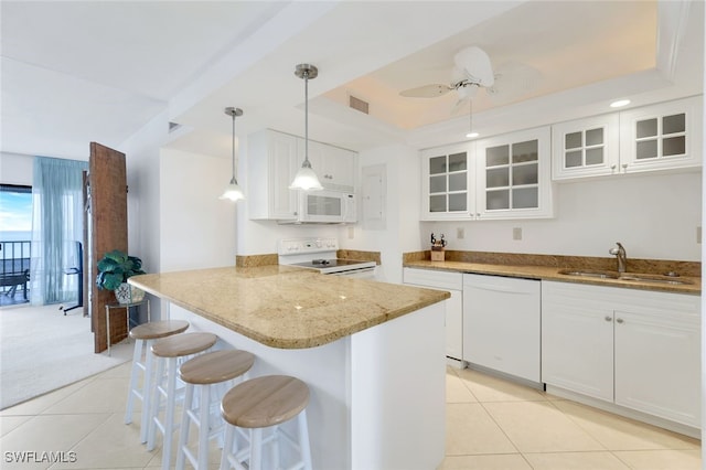 kitchen with ceiling fan, sink, white appliances, a breakfast bar, and white cabinets