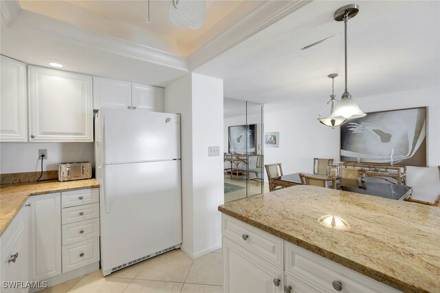 kitchen featuring white cabinets, decorative light fixtures, white refrigerator, and light stone countertops