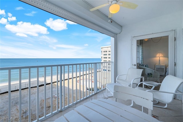 balcony featuring ceiling fan, a water view, and a beach view