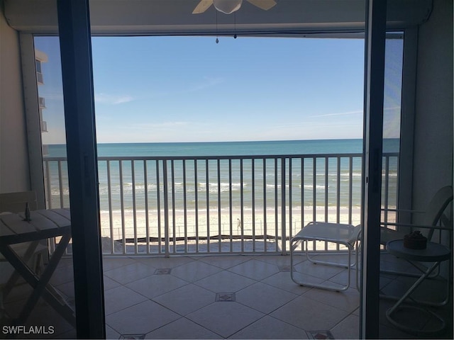 balcony featuring ceiling fan, a water view, and a view of the beach