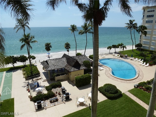 view of pool featuring a water view and a beach view