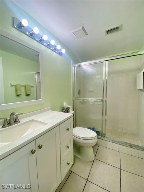 bathroom featuring tile patterned floors, toilet, an enclosed shower, and vanity