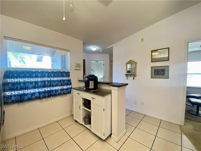 kitchen with white cabinetry, kitchen peninsula, and light tile patterned floors