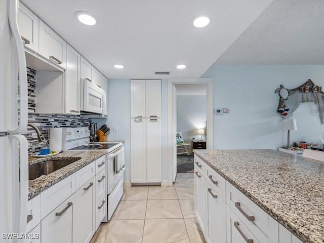 kitchen featuring white cabinets, light stone counters, backsplash, white appliances, and light tile patterned floors