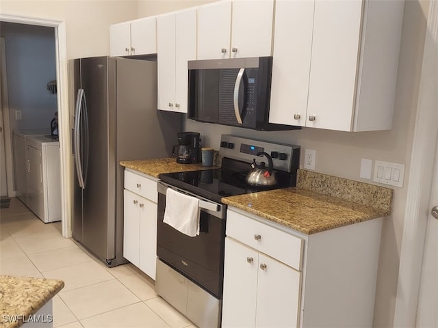 kitchen with stainless steel electric range oven, light tile patterned flooring, white cabinetry, washing machine and clothes dryer, and light stone countertops