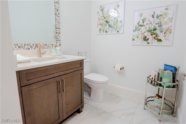 bathroom featuring marble finish floor, vanity, toilet, and baseboards