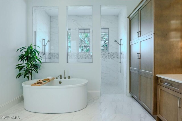 bathroom with marble finish floor, a marble finish shower, baseboards, and a freestanding tub