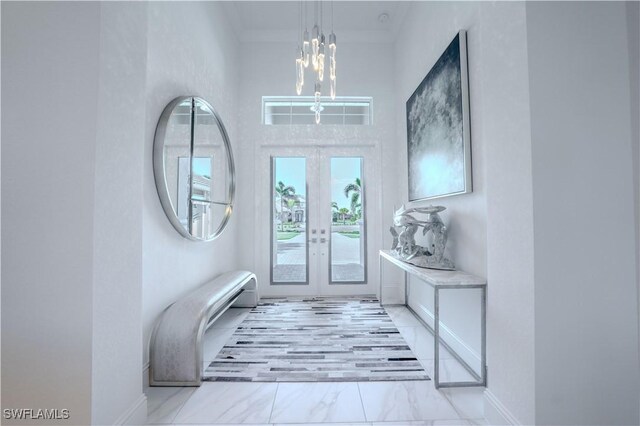 entrance foyer with crown molding, french doors, and an inviting chandelier