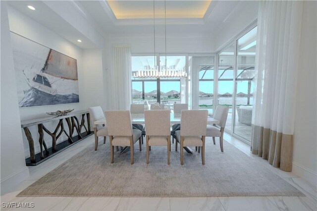 dining area featuring a raised ceiling and a notable chandelier