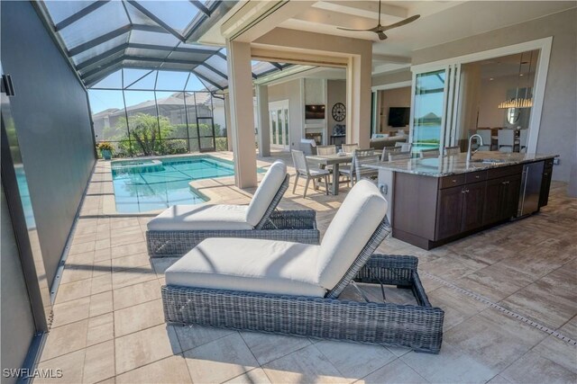 view of pool featuring ceiling fan, a lanai, an outdoor wet bar, area for grilling, and a patio