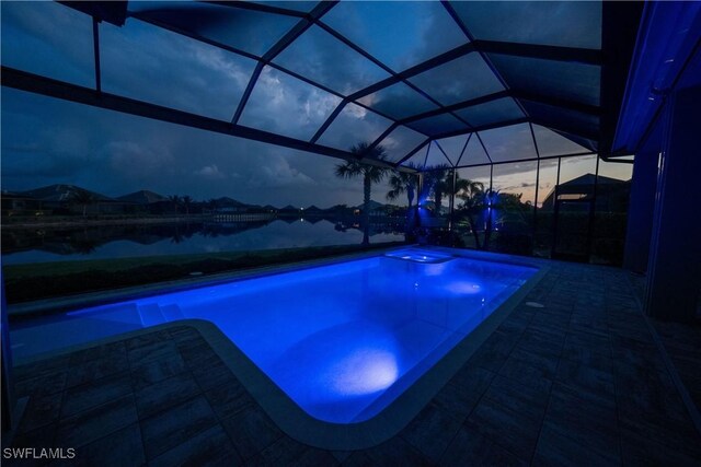 pool at dusk featuring glass enclosure and a patio