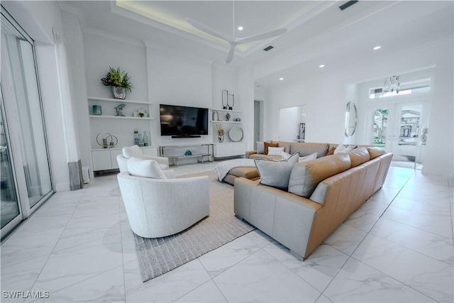 living room featuring an inviting chandelier, crown molding, a high ceiling, and a tray ceiling