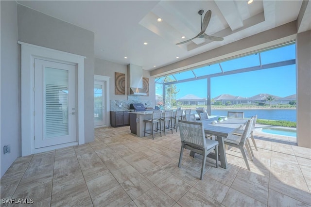 dining area with ceiling fan and a water view