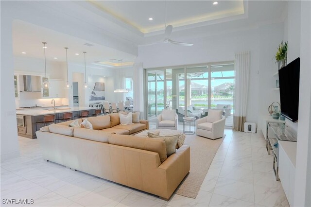 living area with recessed lighting, a raised ceiling, marble finish floor, and a towering ceiling