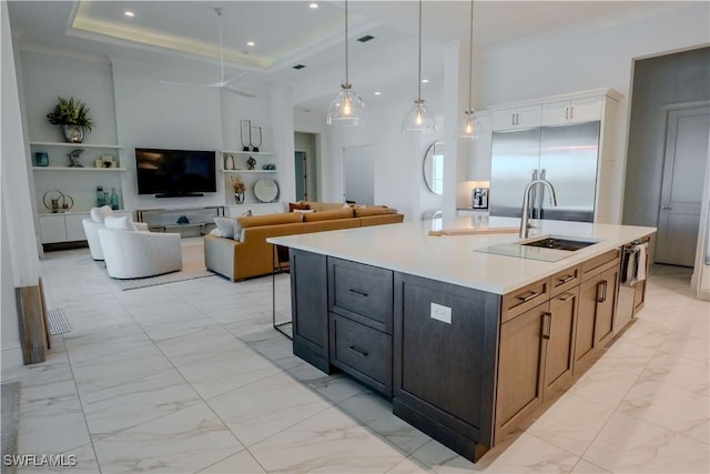 kitchen with marble finish floor, light countertops, a sink, an island with sink, and built in refrigerator