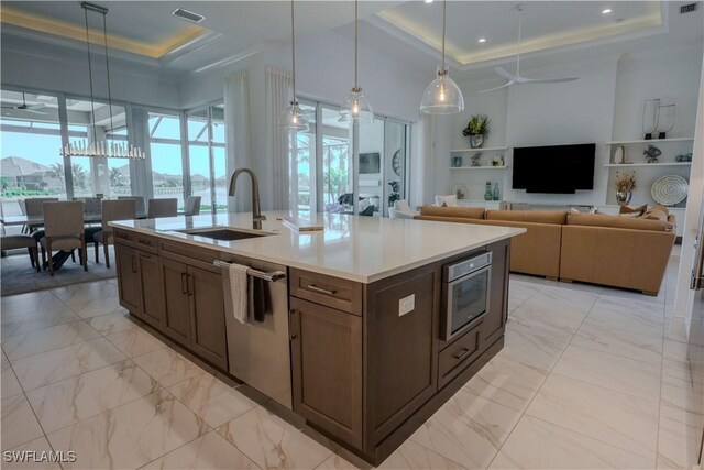 kitchen featuring a raised ceiling, sink, stainless steel dishwasher, ceiling fan, and decorative light fixtures