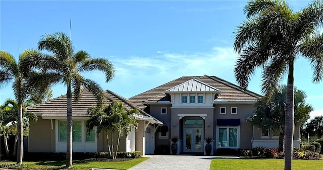 view of front of property featuring a front yard, decorative driveway, french doors, and stucco siding