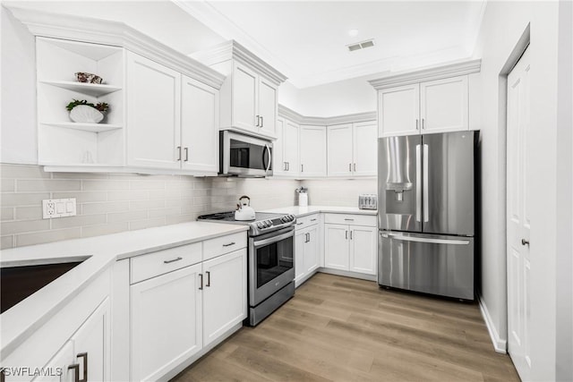 kitchen with backsplash, white cabinetry, light hardwood / wood-style flooring, and appliances with stainless steel finishes