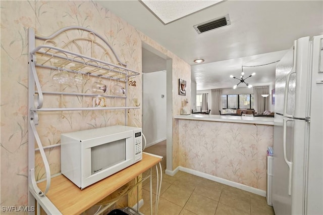 kitchen featuring white appliances, light tile patterned floors, and a chandelier