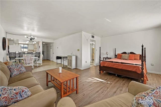 bedroom featuring white fridge, an inviting chandelier, and light hardwood / wood-style flooring