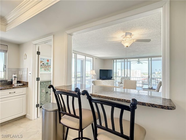 kitchen with dark stone countertops, a breakfast bar, white cabinets, and plenty of natural light