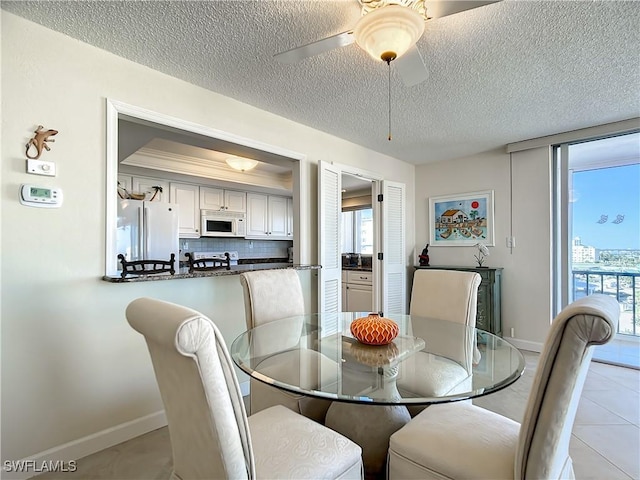 tiled dining area with ceiling fan and a textured ceiling