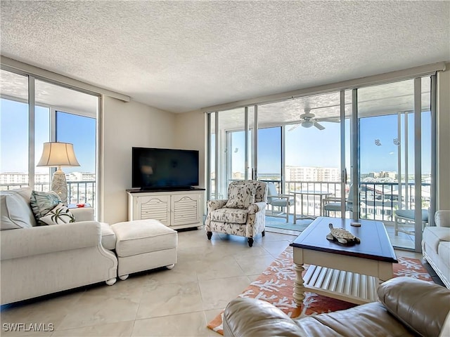 tiled living room featuring a textured ceiling, a wall of windows, and ceiling fan