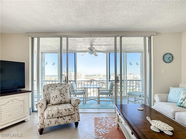 living room featuring ceiling fan, light tile patterned flooring, a healthy amount of sunlight, and a textured ceiling