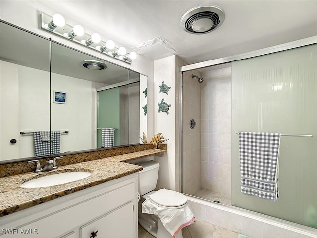 bathroom with tile patterned floors, vanity, toilet, and a shower with shower door