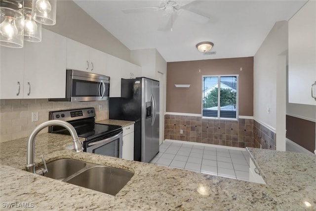 kitchen with vaulted ceiling, sink, white cabinetry, stainless steel appliances, and light tile patterned floors