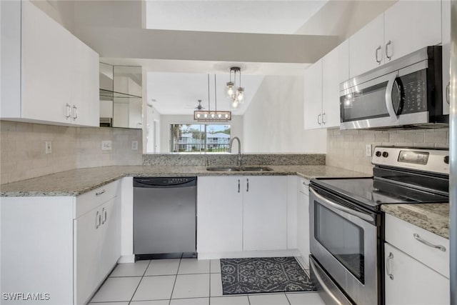 kitchen with decorative light fixtures, tasteful backsplash, sink, white cabinetry, and stainless steel appliances