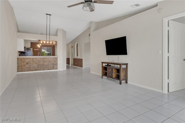 unfurnished living room with lofted ceiling, light tile patterned flooring, and ceiling fan with notable chandelier