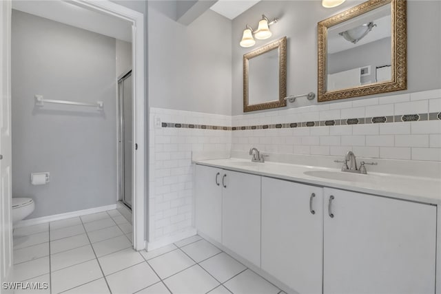 bathroom featuring toilet, vanity, tile walls, tile patterned floors, and an enclosed shower