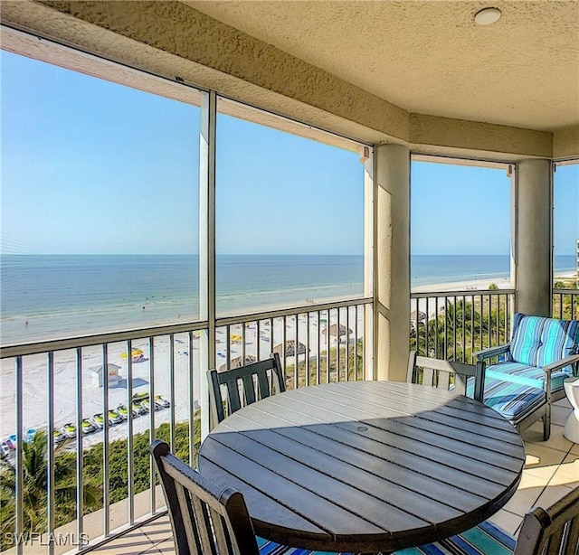 sunroom with a water view and a beach view