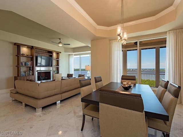 dining room with ceiling fan with notable chandelier, a raised ceiling, and crown molding