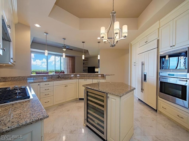 kitchen featuring sink, hanging light fixtures, wine cooler, built in appliances, and a kitchen island