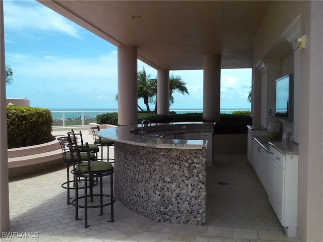 view of patio with a water view, area for grilling, and an outdoor wet bar