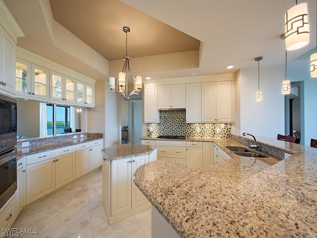 kitchen featuring a center island, sink, hanging light fixtures, light stone counters, and kitchen peninsula