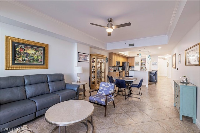 tiled living room with a tray ceiling, ceiling fan, and crown molding