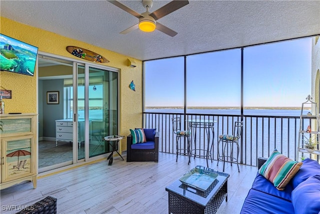 sunroom with a water view and ceiling fan