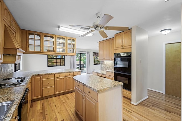 kitchen featuring tasteful backsplash, a center island, black double oven, and stainless steel gas stovetop