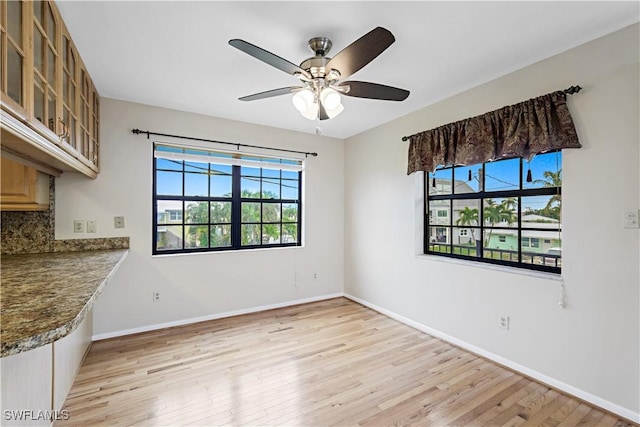 unfurnished dining area with ceiling fan and light wood-type flooring