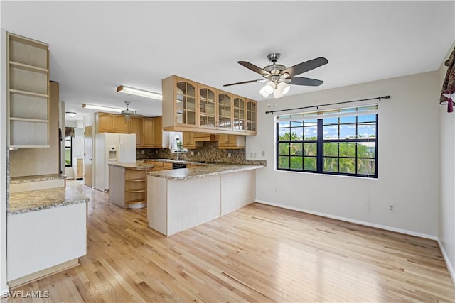 kitchen with tasteful backsplash, ceiling fan, white refrigerator with ice dispenser, and kitchen peninsula