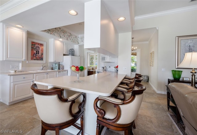 kitchen with a breakfast bar, white appliances, white cabinetry, and tasteful backsplash