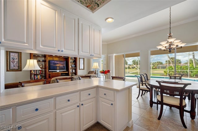 kitchen with white cabinets, pendant lighting, kitchen peninsula, and a chandelier