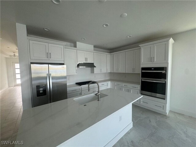 kitchen featuring light stone counters, stainless steel appliances, white cabinetry, and sink